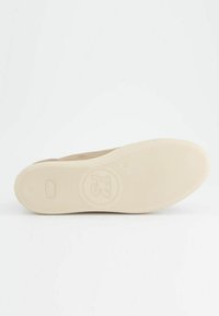 Canvas-Sneaker mit einem hellbraunen Obermaterial und weißer Gummisohle. Verfügt über ein strukturiertes Muster auf der Sohle und ein Logo-Emblem. Klassisches low-top Design.