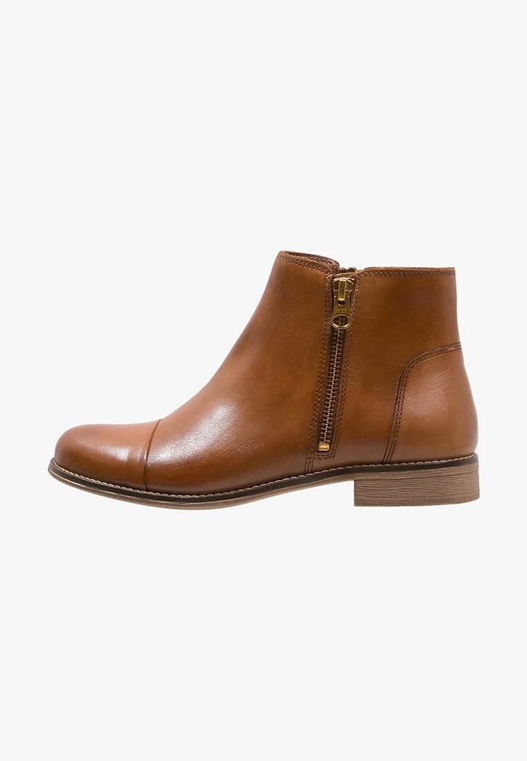 Bottine en cuir marron avec fermeture éclair latérale, petit talon empilé et détails cousus le long de la semelle et de la tige.