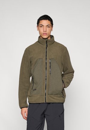 Medvilninis striukė alyvuogių žalia spalva su aukštu apykakliu, dviem priekinėmis kišenėmis su užtrauktukais, tekstūruotu audiniu ir kontrastingais lygiais skydeliais.