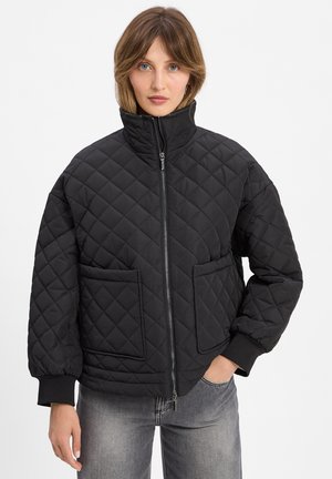 Schwarze gesteppte Jacke mit hohem Kragen, durchgehendem Reißverschluss und zwei Fronttaschen. Mit gerippten Bündchen und einer kastigen Silhouette.