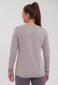 Langærmet atletisk top i lysegrå tekstureret stof med rund halsudskæring og reflekterende detaljer bagpå, tætsiddende design, glat tekstur.