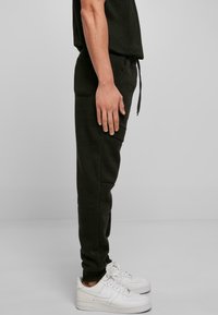 Sorte, bløde bomulds sweatpants med snor i taljen, sidelommer, slim fit og ribbede manchetter, kombineret med hvide sneakers.