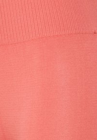 Tecido têxtil coral com textura em ribetes na parte superior e superfície lisa na parte inferior. Cor uniforme sem padrões ou acentos visíveis.