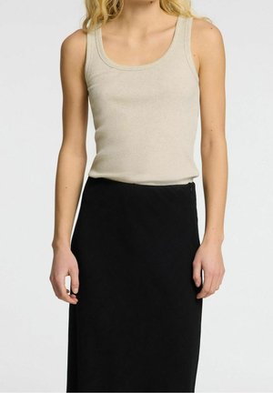Beige ribbet top med rundt halsudskæring, båret med en tætsiddende sort nederdel. Blød tekstur og slank pasform.