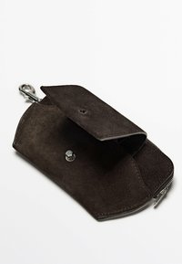 Portefeuille en daim marron avec fermeture éclair, bouton-pression et clip en métal. L'intérieur présente une doublure lisse sans motifs visibles.