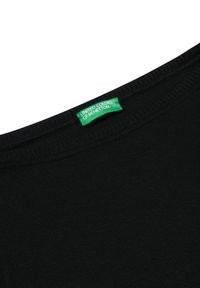 Camiseta negra de cuello redondo, con textura acanalada y detalles cosidos. Presenta una etiqueta verde que dice "UNITED COLORS OF BENETTON."