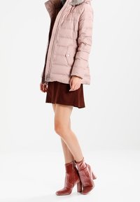 Padded pink jacket with a fur-lined hood, paired with a brown skirt and pink velvet ankle boots featuring a side zipper and block heel.