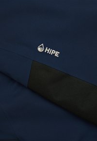 Tessuto blu navy con una texture liscia e un dettaglio in rete nera. Il logo "HIPE" è ricamato in bianco vicino al bordo.