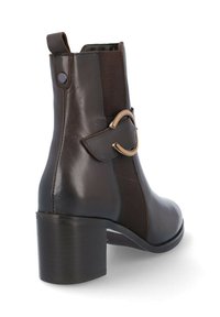 Bota de cuero marrón hasta el tobillo con paneles laterales de elastano, puntera redonda, tacón cuadrado y un acento decorativo de anillo de metal en el lateral.
