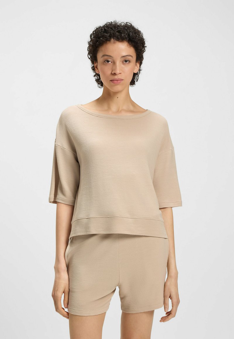 Beżowy zestaw odzieży domowej składający się z luźnej, prążkowanej bluzki z krótkim rękawem i pasujących szortów, z delikatną teksturą i swobodną sylwetką.