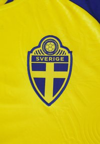 Swedish Football Association emblem with blue and yellow cross on yellow fabric, text "Sverige" and soccer ball with year 1904.