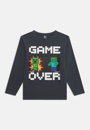 Chemise gris foncé à manches longues avec des personnages de jeu pixelisés et le texte "GAME OVER" en lettres majuscules à l'avant.