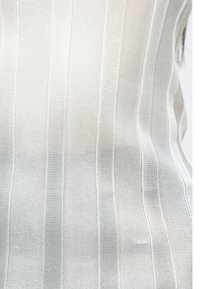 Textúrovaná pletenina v svetlosivej farbe s vertikálnymi žíhanými pruhmi. Povrch má jemný a mierne elastický vzhľad.