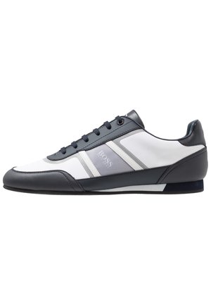 Lavprofileret herresneaker med sorte, hvide og grå paneler, snørebånd og diskrete meshdetaljer på siden.