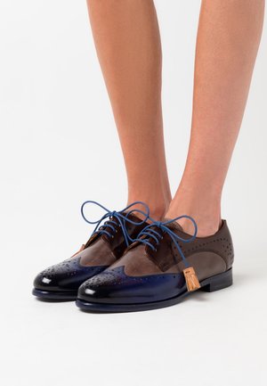 Brown and navy leather oxford shoes with brogue detailing, blue laces, and a decorative tassel, featuring a smooth and textured finish.