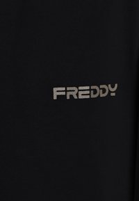 Tela negra con la palabra "FREDDY" en letras metálicas plateadas, textura suave y diseño simple sin patrones ni acentos adicionales.