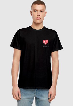 Sort bomulds t-shirt med et rødt hjerte-design med et tyrkisk flagmotiv og ordet "TÜRKİYE" trykt nedenunder i hvid. Korte ærmer.