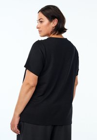 Black short-sleeve t-shirt with a relaxed fit, featuring a round neckline and subtle shoulder detailing. Soft, smooth fabric texture.