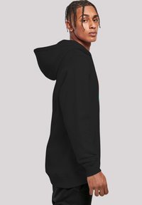 Black hooded sweatshirt with a kangaroo pocket, ribbed cuffs, and hem. Features printed design on the front, smooth texture, and relaxed fit.