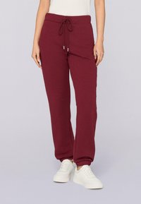 Burgunderfarbene Sweatpants mit einem elastischen Bund, Kordelzug, Seitentaschen und gerippten Bündchen, aus weichem Baumwollmaterial gefertigt.