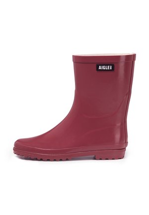 Średniej wysokości błyszczące ciemnoczerwone gumowe kalosze z bieżnikowaną podeszwą i prostokątną czarną naszywką z napisem "AIGLE 1853" w pobliżu góry.