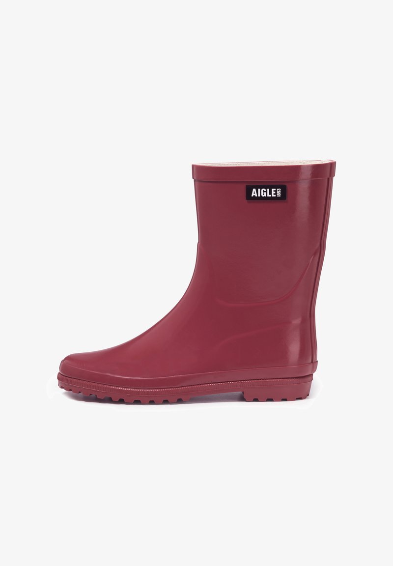 Botte de pluie en caoutchouc rouge foncé brillant de hauteur moyenne avec semelle cramponnée et patch logo rectangulaire noir marqué "AIGLE 1853" près du haut.