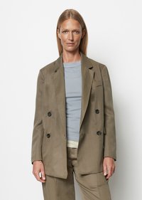 Dvojitě zapínaný olivově zelený lněný blazer se dvěma černými knoflíky. Stylizovaný přes světle šedý top s kulatým výstřihem. Hladká textura, strukturovaný design.