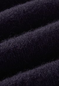 Dunkelblaues Wollgewebe mit einer weichen, strukturierten Oberfläche. Merkmale sind glatte und flauschige Fasern sowie wellenförmige Falten, die Tiefe und Dimension erzeugen.