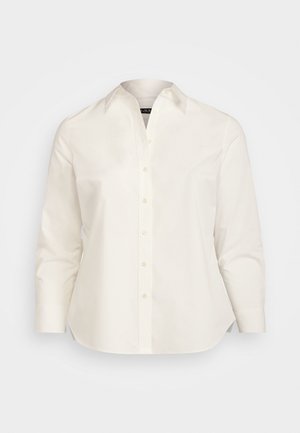 Chemise blanche à manches longues avec col pointu, boutons sur le devant et ourlet légèrement incurvé sur un fond uni.