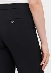 Sorte skræddersyede bukser i glat stof, med en baglomme med knapdetalje og slim fit design, der fremhæver en ren silhuet.