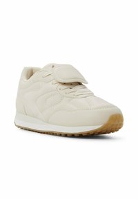 Beige Sport Schuh mit einem glatten Lederoberteil, strukturierten Überzügen, Schnürverschluss und einer Gummisohle mit kleinen Traktionsnoppen.