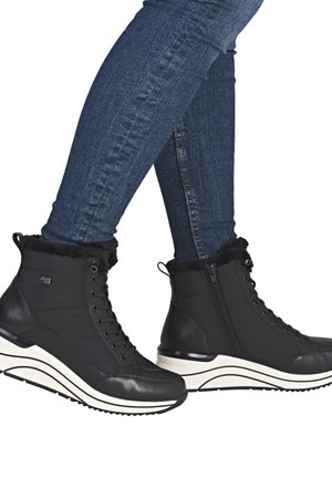Black ankle boots with a smooth leather and soft fabric upper, featuring a fuzzy trim, lace-up front, and a chunky white sole.