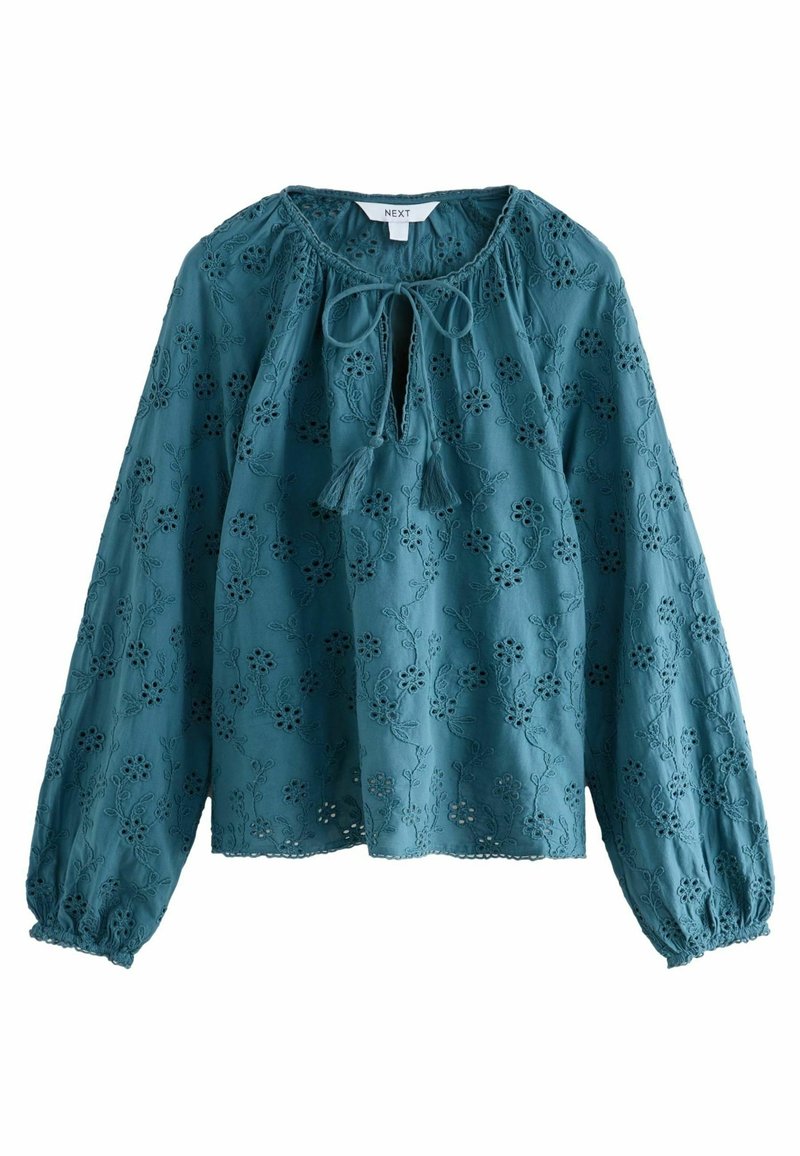 Blusa ricamata color teal con maniche lunghe, polsini arricciati, scollatura rotonda e chiusura con fiocco, caratterizzata da motivi floreali intagliati.