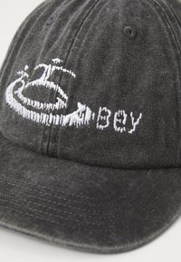 Grå bomullsbasscaps med brodert hvit logo og tekst. Har en buet skjerm og sekspaneldesign med ventilasjonsåpninger.