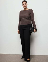 Długo rękawowa bluzka w metaliczno-brązowym kolorze z dekoltem typu łódka, zestawiona z wysokim stanem czarnymi spodniami i czarną plecioną torebką.