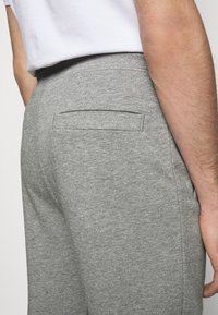 Pantalones de chándal grises de algodón con un acabado texturizado y un bolsillo trasero, que cuentan con una cinturilla acanalada y un corte casual.