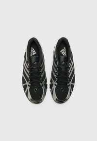 Baskets noires de sport avec dessus en maille et synthétique, présentant des accents gris et trois rayures blanches, avec un design à lacets et un bout rond.