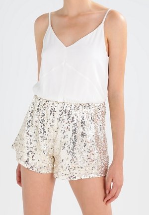Haut en satin blanc à bretelles spaghetti associé à un short en sequins dorés et argentés scintillants avec une taille élastique et une coupe décontractée.