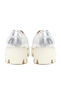 Chaussures blanches épaisses à semelle plateforme avec dessus en cuir métallisé argenté, vues de dos sur fond blanc.