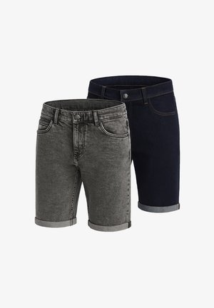 Hvid t-shirt med subtil sprinklet mønster, parret med mørkegrå denim shorts med opkrøllede kanter og hvide sneakers med sorte detaljer.