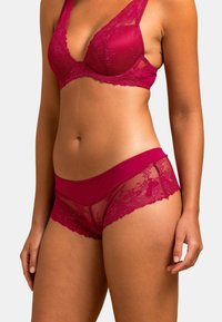 Ensemble de lingerie en dentelle framboise comprenant un soutien-gorge et une culotte assortis, avec des panneaux en mesh transparent et des motifs floraux. La culotte a une taille lisse pour plus de confort.