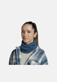 Gaiter blu navy realizzato in tessuto morbido, con un'etichetta del logo. Indossato con una camicia a quadri blu chiaro e bianca, creando un look a strati.