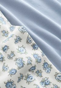 Tissu bleu clair côtelé associé à un tissu blanc avec un motif floral bleu. Les textures sont lisses et légèrement texturées.