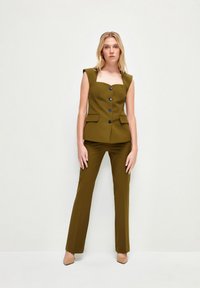 Olivengroene op maat gemaakte blazer met vierkante halslijn, korte mouwen en vijf zwarte knopen; gecombineerd met bijpassende slim-fit broeken.