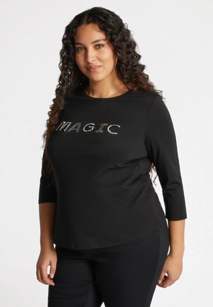 Zwarte blouse met lange mouwen met het woord "MAGIE" in zilveren strass-steentjes. Gemaakt van een soepele stof met een relaxte pasvorm en ronde hals.
