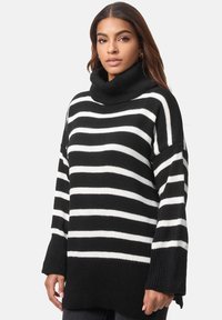 Schwarz-weißer gestreifter Pullover mit hohem Rollkragen, lockerer Passform und gerippten Bündchen, der eine gestrickte Textur und ein entspanntes Design zeigt.