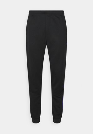 Pantalon de survêtement noir fuselé avec taille et poignets élastiques, présentant de fines rayures verticales bleues sur la partie extérieure des jambes inférieures.