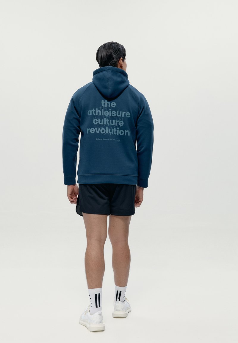 Felpa navy con testo grafico sul retro, abbinata a pantaloni corti neri e calze bianche con righe nere. Tessuto morbido e cappuccio regolabile.