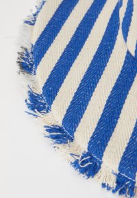 Kruhový textil s modro-krémovými diagonálnymi pruhmi a strapcovým okrajom. Textúra je tkaná s výrazným rybím kostrom.