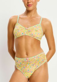 Ensemble de bralette en dentelle florale jaune et de culotte taille haute avec des bordures vert menthe et de petits embellissements roses au centre ; texture douce.